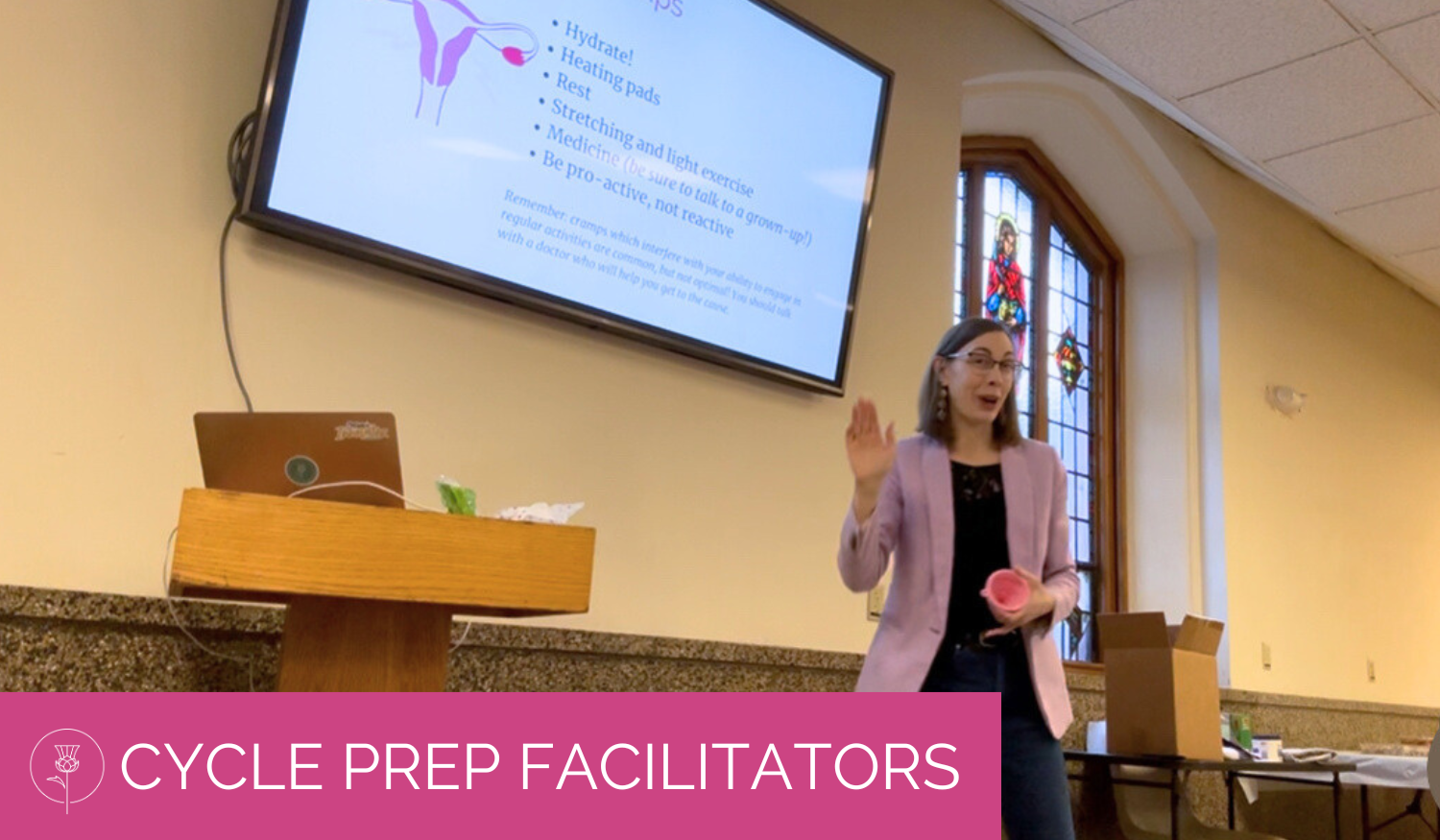 christina holds a funnel while giving cycle prep presentation slide deck in a parish hall