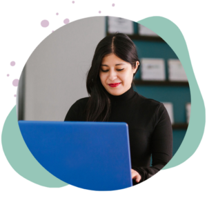 woman in black turtleneck works at computer and smiles
